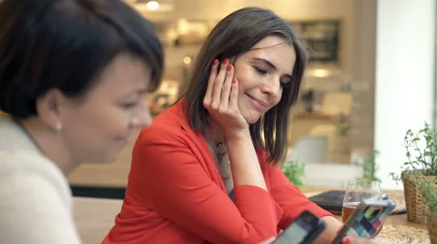 Two beautiful girlfriends using smartphone and talking in cafe, 4K Stock Footage 68152294