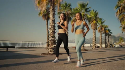 Two beautiful girls jogging at sunset or sunrise on beach. Young caucasian women Vídeos de archivo 211480778