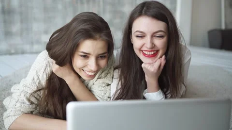 Two beautiful girls look the laptop in summer cafe Stock Footage 59343910