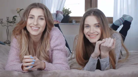 Two beautiful girls smiling  while lying on bed. 動画素材 62340006