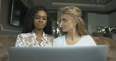 Two beautiful happy multirace girlfriends are using the laptop and laughing. 4k. Stock Footage 84055432