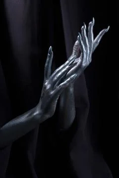 Two beautiful man's hands in silver paint on a black background Stock-Fotos