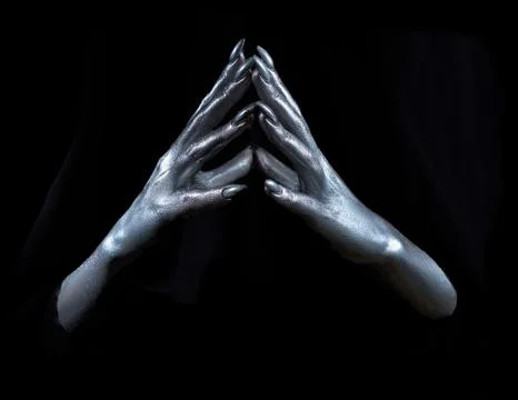 Two beautiful man's hands in silver paint on a black background Stock Photos