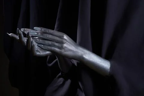 Two beautiful man's hands in silver paint on a black background Stock-Fotos