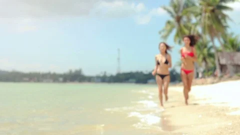 Two beautiful models in bikinis running along the shore of a beach Vidéo 72653755
