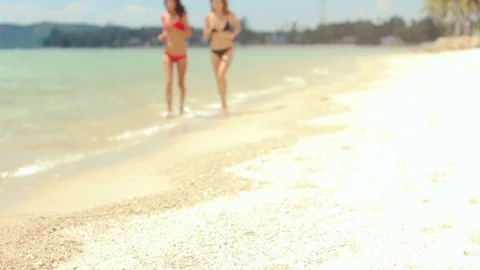 Two beautiful models in bikinis running along the shore of a beach Stockbeeldmateriaal 72655458