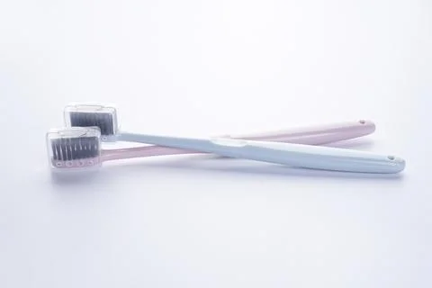 Two beautiful multi-colored toothbrushes with black shields, on a white backg Stock Photos