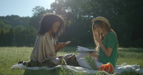 Two beautiful multi race girlfriends are having the picnic in the park. The afro Stock Footage 84640118