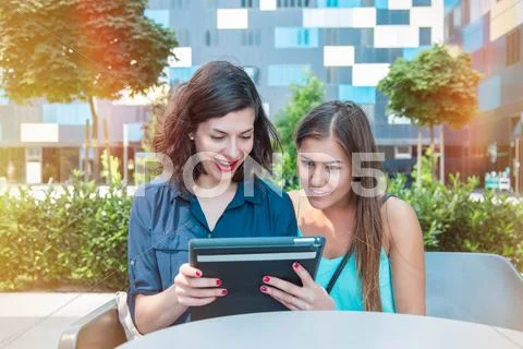 Two Beautiful Women Having Fun While Using A Tablet