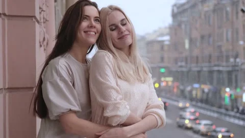 Two beautiful women hugging while standing on the balcony in the city view Stock Footage 155735406