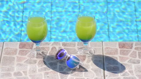 Two beautiful yellow-green-blue cocktails with straws, sunglasses by pool 库存影片 132644280