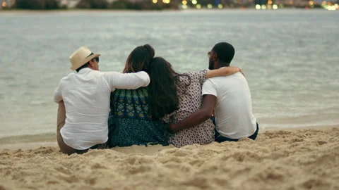 Two beautiful young couples cuddling on the beach, looking at the horizon close Stock Footage 199462055