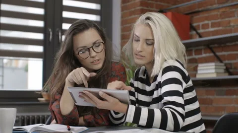 Two beautiful young girls studying at modern loft apartment. Stock Footage