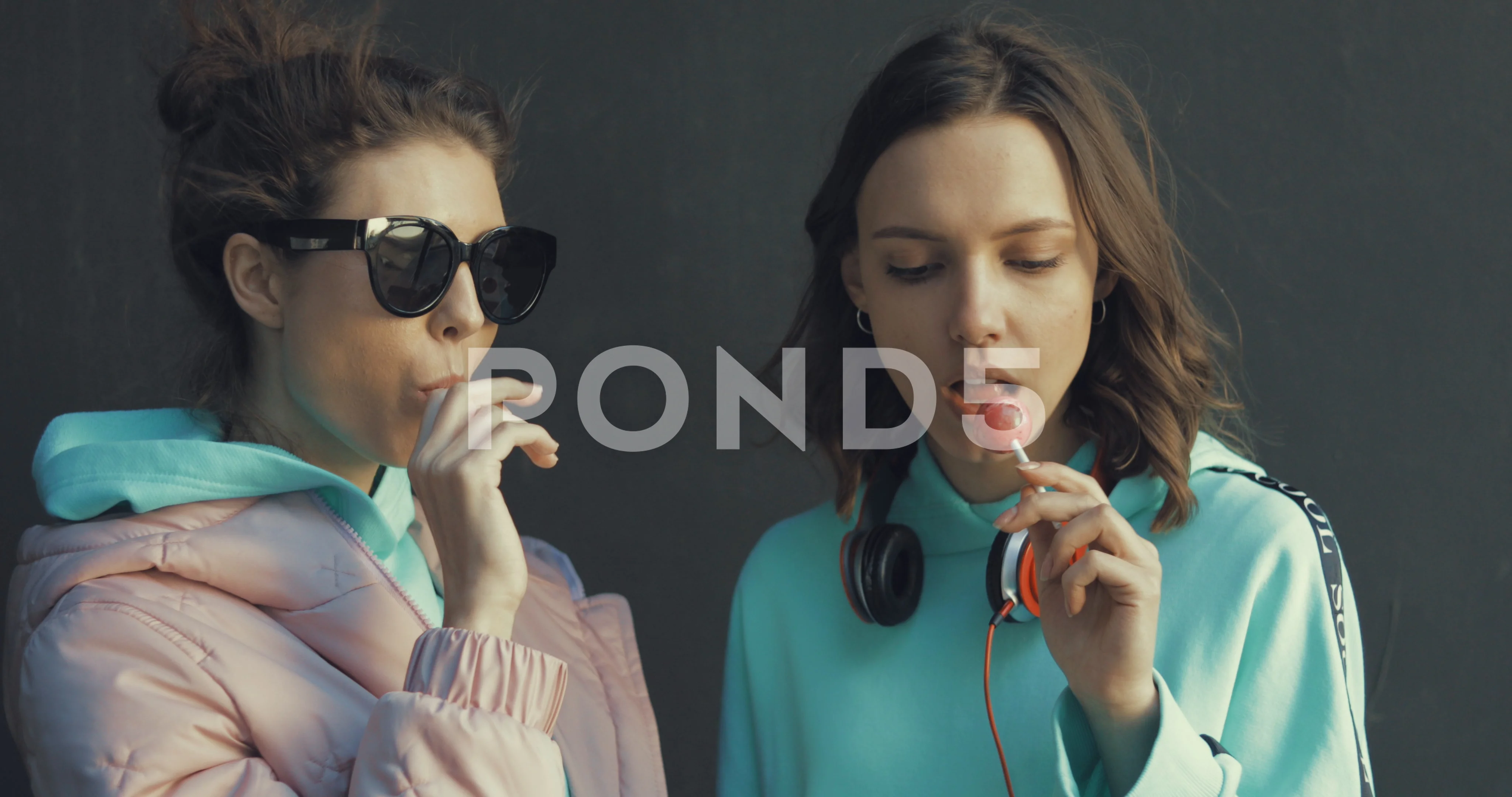 two beautiful young girls sucking lollipops