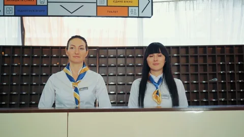 Two beautiful young stylish receptionists at a reception desk, welcome guests Stock Footage 129504649