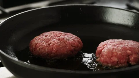 Two Beef patty's gently sizzling in a hot cast iron pan, two in frame. Stock Footage 92149726