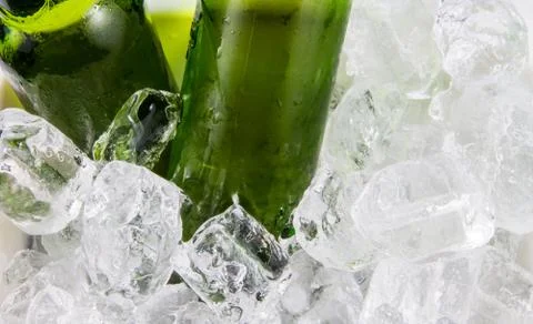 Two beer bottles getting cool in ice cubes Stock Photos