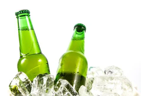 Two beer bottles getting cool in ice cubes Stock Photos