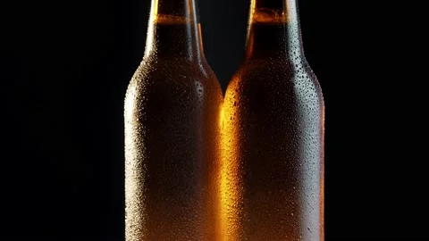 Two beer bottles rotating on black background Stock Footage 132560875