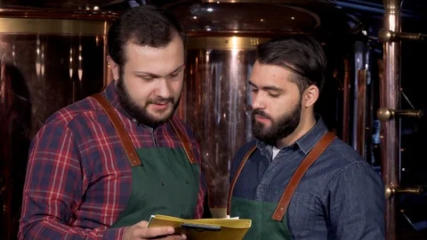 Two beer makers smiling to the camera, while working at their brewery Stock Footage 103047373