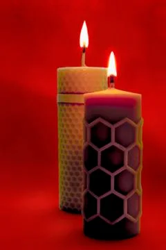 Two beeswax candles flame on a red background Stock Photos