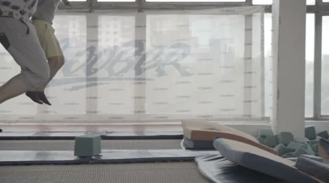 Two beginner  acrobat doing a somersault  with a trampoline in the foam pit Stock Footage 61205314