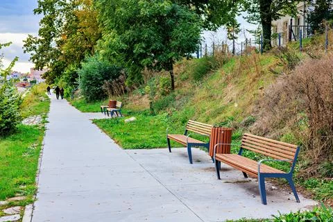 Two benches and a trash bin on a path in the park. Stock Photos