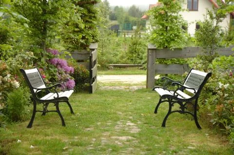 Two benches on foot path in garden Stock Photos