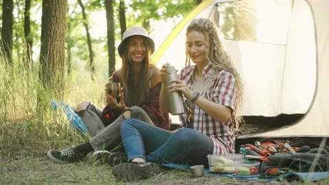 Two best friends are sharing a joyful moment together by their cozy tent, fully Stock Footage 285354965