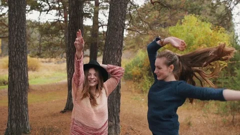Two beutiful girls dancing in the autumn forest and have fun. Stock Footage 69764635