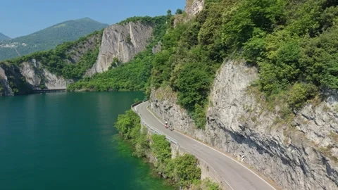 Two bicycle riders moving on coastal highway by Lake Iseo, Italy Stock Footage 341751187
