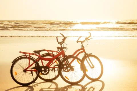 Two bicycles and empty beach without people.no body at sunset Stock Photos