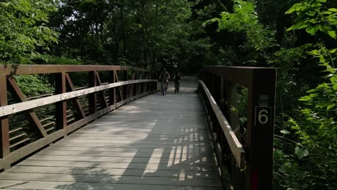Two bicyclists crossing marker 6 on the Katy Trail Stock Footage 243601931