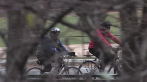 Two Bicyclists Riding Through The Park Passing Trees Stock Footage 59570153
