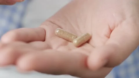 Two big transparent cylindrical pill capsules with green powder inside fall into Stock-Footage 147185730