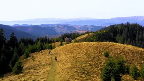 Two bikers riding down a mountain trail in autumn sunny day. Cross country biker Stock Footage 150599044