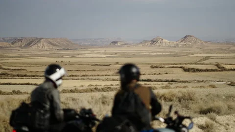Two bikers standing in the middle of the desert looking at the mountain backdrop Stock Footage 221435326