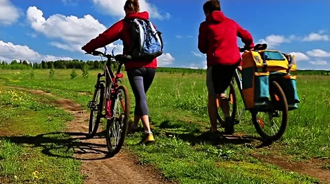 Two bikers walk with bikes on the field road 스톡 동영상 57684208