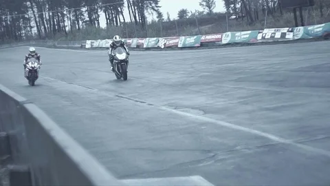 Two bikes pass a straight section of competition and come into a turn Stock Footage 70325075