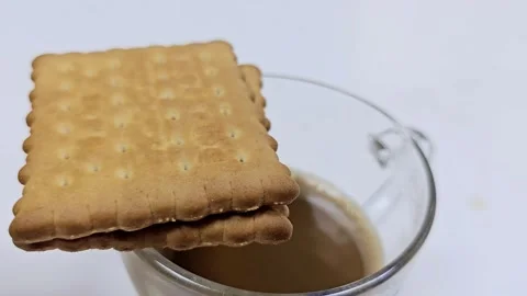 Two biscuits rest atop a clear glass mug filled with a creamy Video stock 312003133