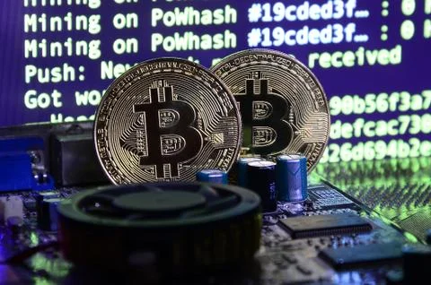 Two bitcoins lies on a videocard surface with background of screen display of Stock-Fotos