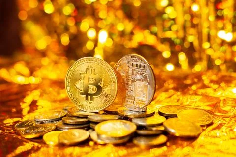 Two bitcoins on a stack of coins on a gold background and a bokeh Foto stock