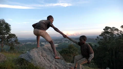 Two Black African Children help each other to climb a hill. Stock Footage 194538955
