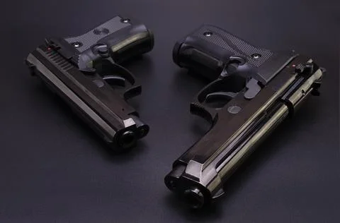 Two black automatic pistols on a black background Stock Photos