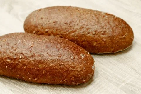 Two black baked bread on a light wooden background Stock Photos
