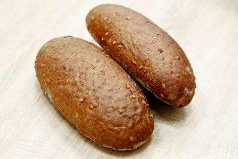 Two black baked bread on a light wooden background Stock Photos