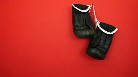 Two black boxing gloves hanging on red wall. Man's hand takes gloves Stock Footage 150085235