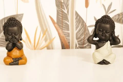 Two black Buddha figures on a white piece of furniture. Stock Photos