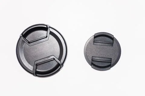 Two black camera lens caps of different sizes, a small and a large lens cap on a Foto stock