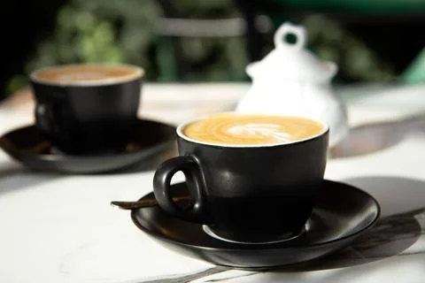 Two black ceramic cup of coffee on a marble table on an open terrace Stock Photos